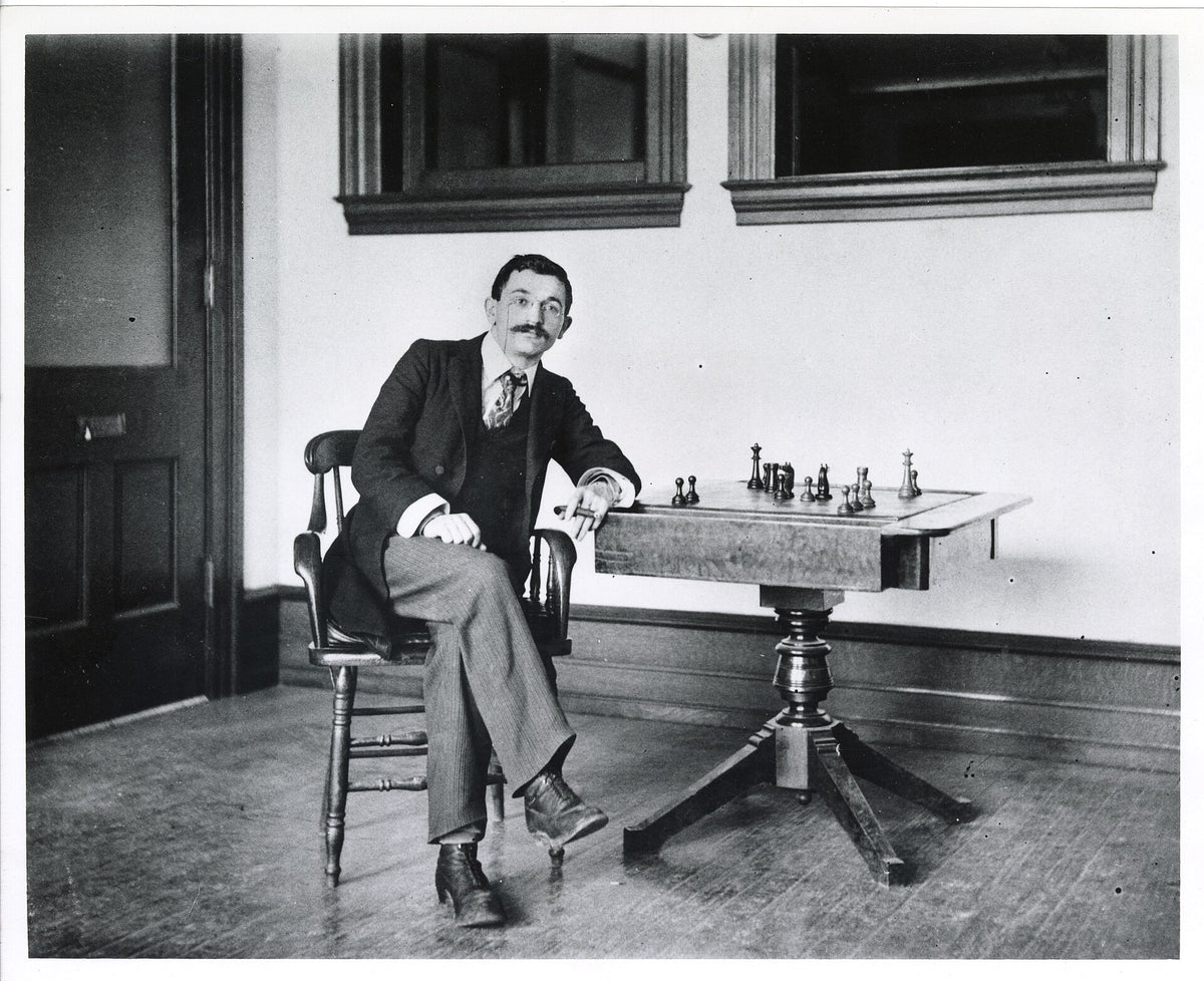Emanuel Lasker sentado junto a un tablero de ajedrez en 1894